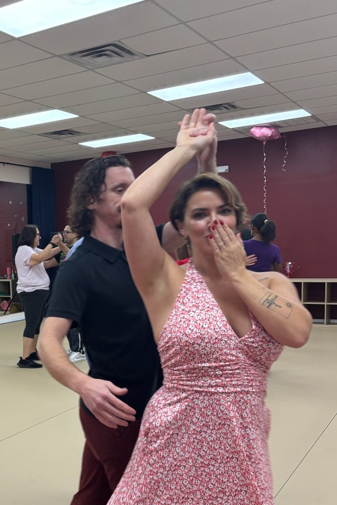 A couple dancing together on the B3 studio floor, her hand raised mid-turn, other couples behind them