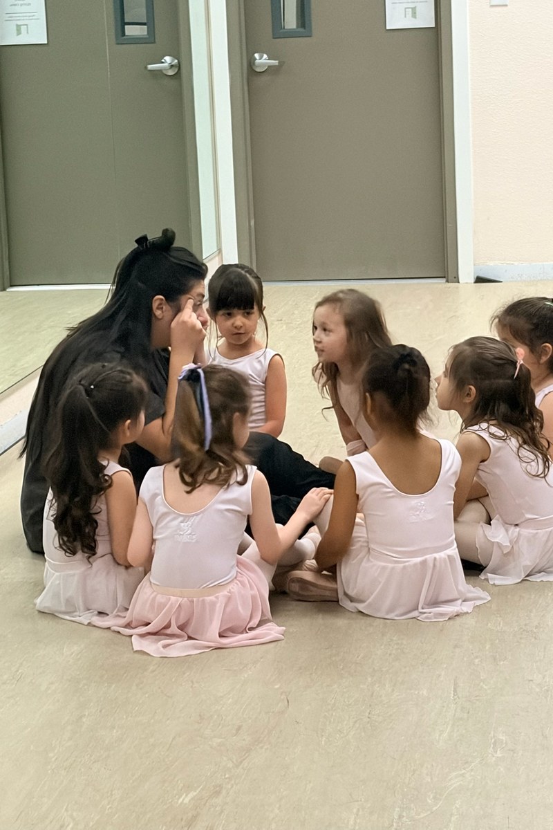 Sprouts dancers in pink leotards sitting in a circle with their teacher